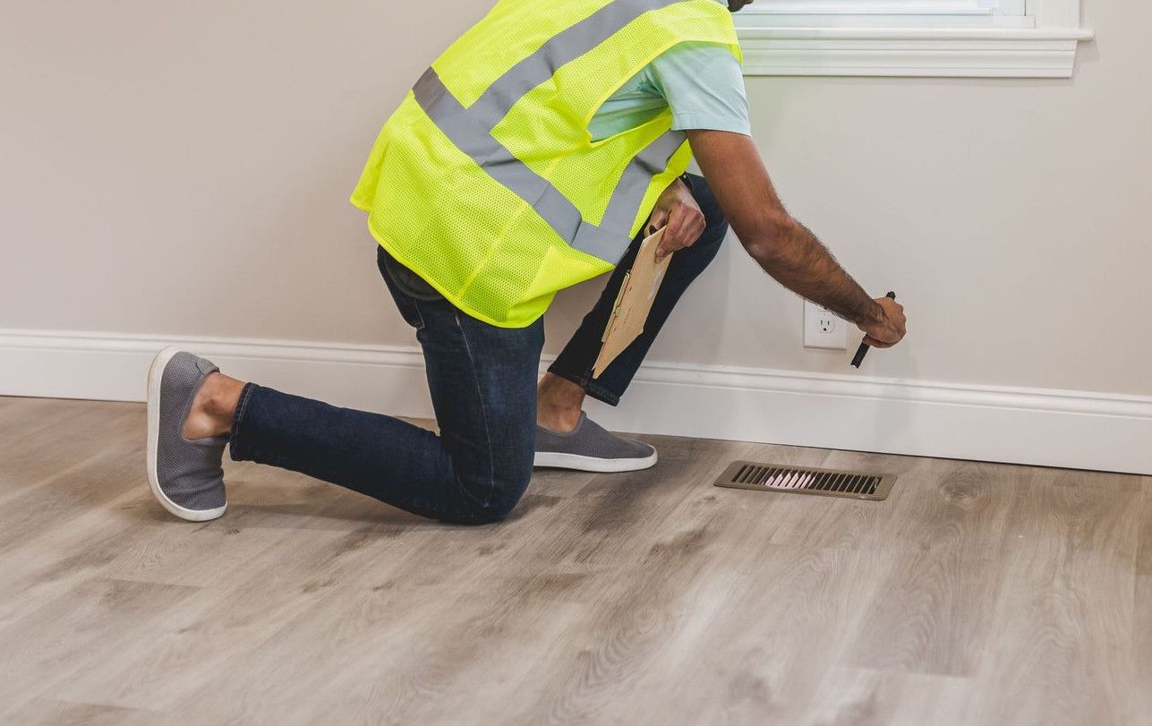 Worker in safety gear inspecting a room's corner for renovation or improvement.